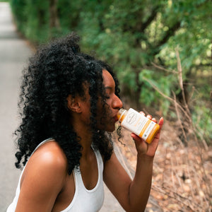 person wearing workout clothes drinking spicy lemon cold pressed juice on hiking trail
