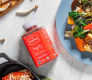 Bottle of dragonfly juice beside a plate of vegetables