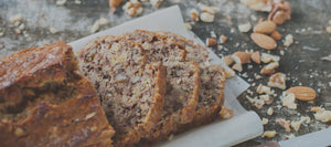 A baked good with crushed almonds on a wooden table.