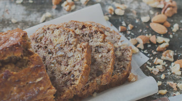 A baked good with crushed almonds on a wooden table.