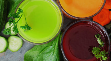 Top view of juice on a wooden table alongside vegetables.