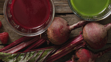 Juice, beets, and apples on a wood table.