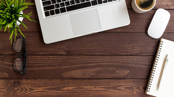 Laptop on wooden desk with plant.