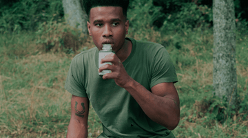 Man enjoying a green Pulp and Press juice outside with a green forest backdrop.