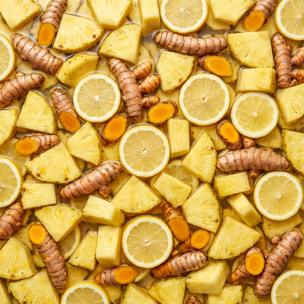 A close-up of sliced lemons, pineapples, and turmeric in a water bath.