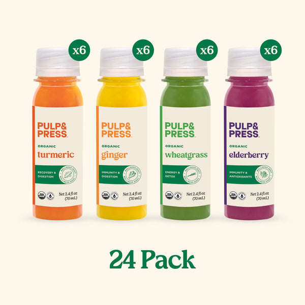 Four bottles of Pulp & Press organic juices with labels for turmeric, ginger, wheatgrass, and elderberry on a white background.