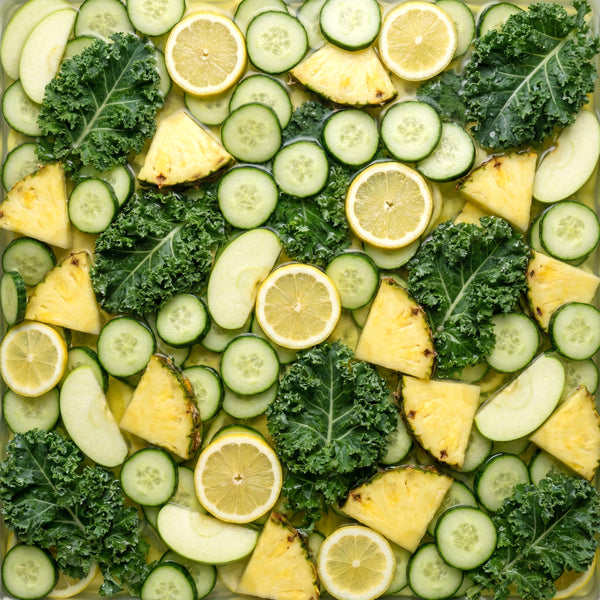 Sheet pan with sliced cucumbers, lemons, pineapples, green apples and kale.