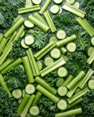 Green vegetables including cucumbers, celery, and kale arranged in a pattern.