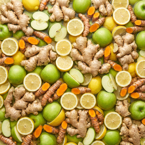 Assorted fruits and vegetables including ginger, apples, and lemons arranged in a pattern.