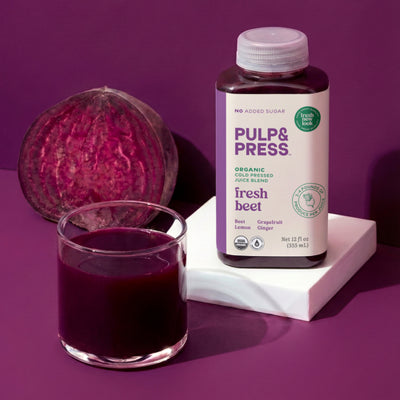 Pulp & Press organic cold pressed fresh beet juice bottle with a glass of juice and a beet on a purple background