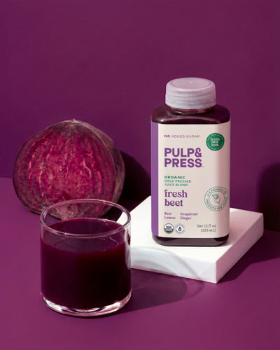 Pulp & Press organic beet juice bottle with a glass of juice and beet root on a purple background
