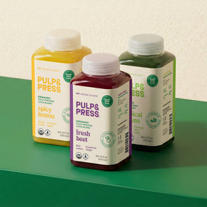 Three bottles of Pulp & Press cold pressed juice on a green surface with a light background
