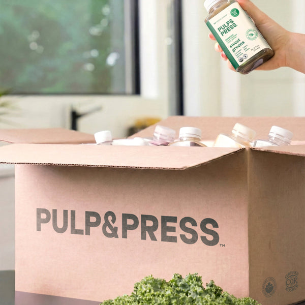 Person holding a bottle of 'Pulp&Press' product above a cardboard box with the brand name.