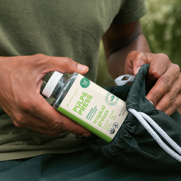 Person holding a jar labeled 'Pulp & Press' with a green background
