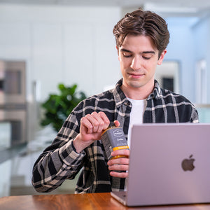person holding cold pressed juice with laptop